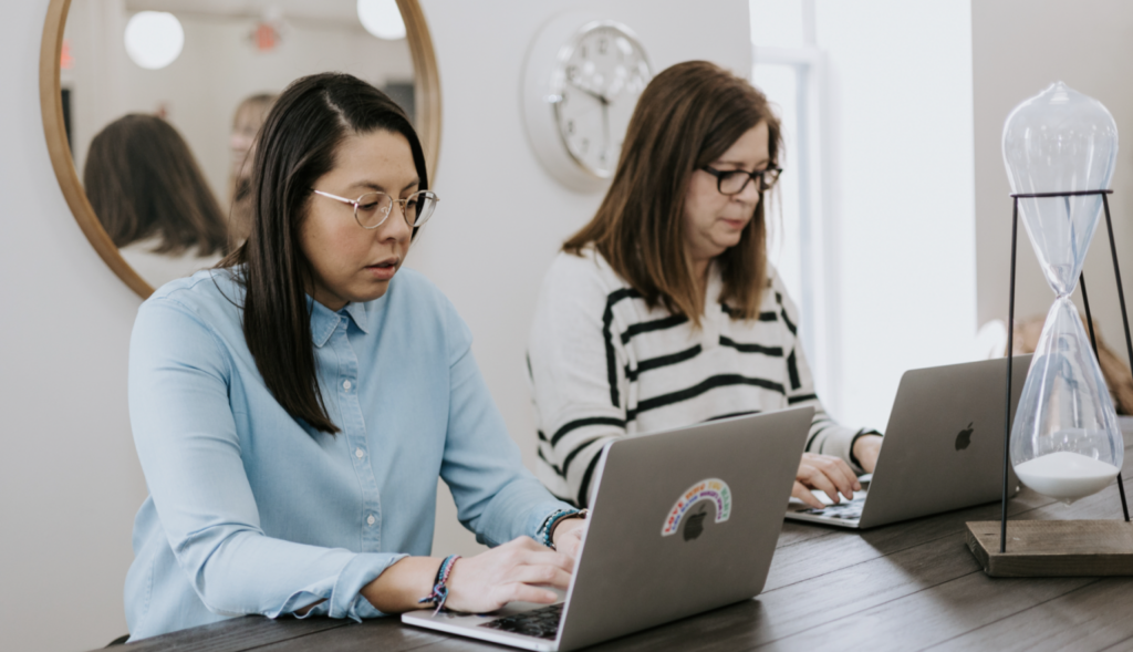 Two women at a table in an office setting. 