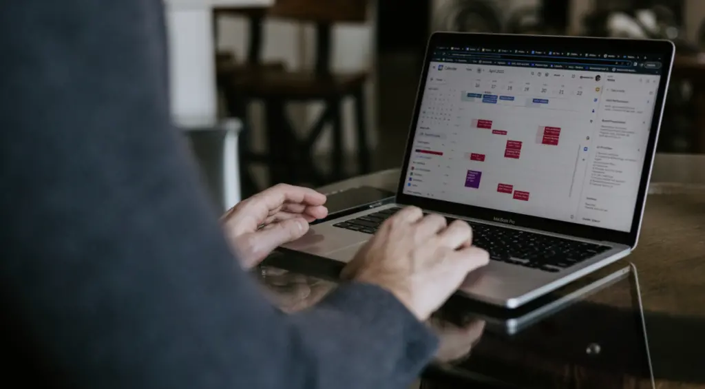 A man sitting at a computer working on a calendar for ERG management software.