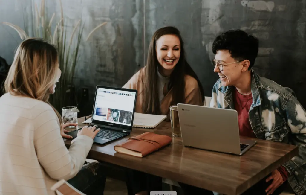 A picture of 3 women at a table laughing in discussion of growing employee resource groups. 