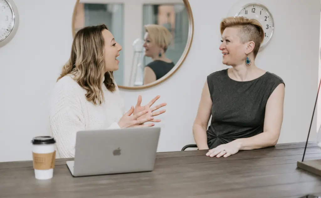 Two women in an office energetically discussion ERG DEI strategies. 